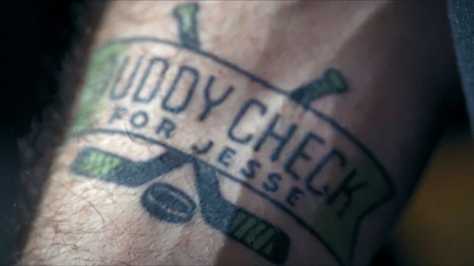 A 'Buddy Check for Jesse' tattoo on a forearm